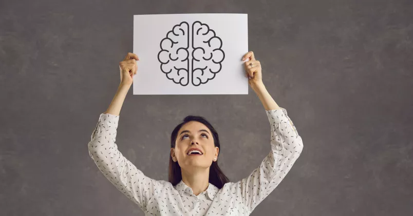 Hjärnsmart. En kvinna håller upp en skylt med en tecknad hjärna på. Glad. 
