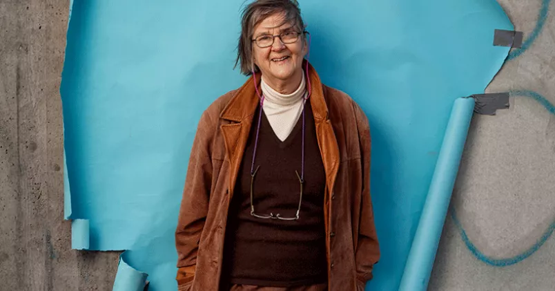 En webbapp som håller koll på stressnivån och som hjälper en att hitta metoder för att tagga ner – det hoppas Marie Åsberg att hon och hennes forskarteam snart har fått fram. Marie Åsberg framför en vägg med blå fond.
