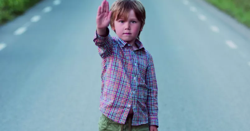 Träna dig på att våga säga stopp! Pojke står på väg och håller upp handen i stopptecken.