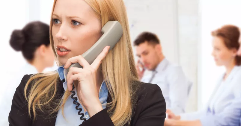 Har du rätt till mer semester än du tror? Mer än chefen tror? Ta reda på vad som gäller - prata med ditt fackförbund! Kvinna talar i telefon med kollegor i bakgrunden.