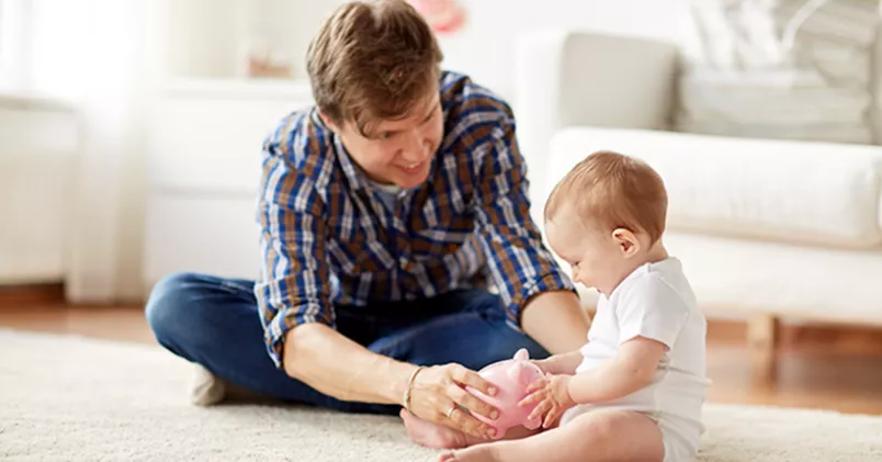 Föräldralön från arbetsgivaren. Pappa och bebis leker på golvet.