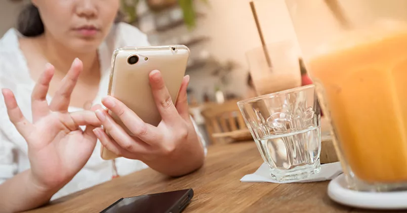 Börjar du arbetsdagen med att kolla jobbmejl redan till frukost? Kvinna kollar mejlen i mobilen vid frukostbordet.