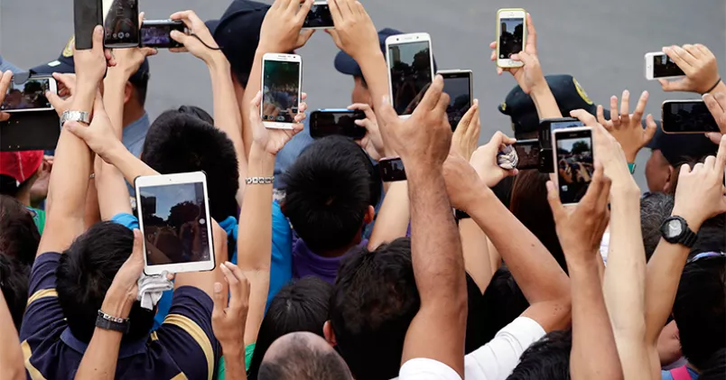 Grupp av människor tar selfies med mobiltelefoner.