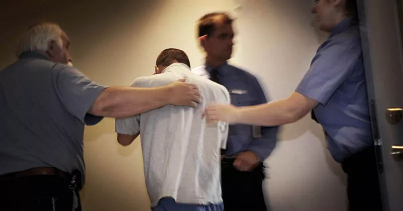 Mannen på bilden har inte med artikeln att göra.  Man leds av häktespersonal.