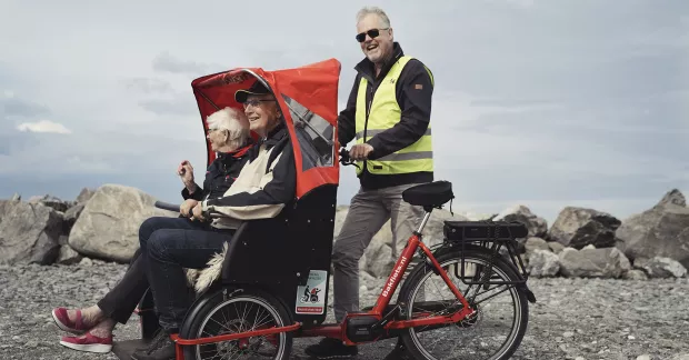 Man som skjutsar två äldre på specialbyggd cykel