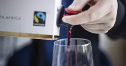 Person fyller på vinglas från bag in box med rödvin.