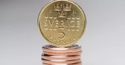 En femkrona balanserar på en stapel med mynt av annan valör.